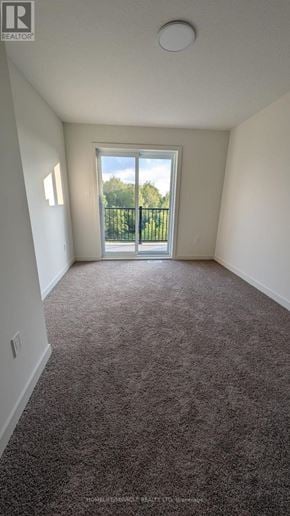 Guelph (Riverside Park) townhouse for rent - A room with a carpeted floor and a sliding glass door leading outside.
