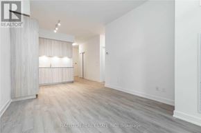 Toronto (Niagara) condo for rent - A spacious room with wooden flooring and white walls.