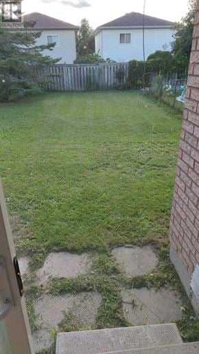 Barrie (Holly) townhouse for rent - A backyard with a wooden fence and a small tree.
