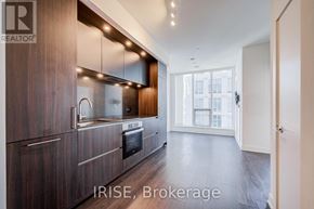 Toronto (Waterfront Communities) condo for rent - A modern kitchen with dark wood cabinets and a stainless steel oven.