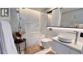 Vancouver apartment for rent - A white bathroom with a marble tile wall and a white toilet.