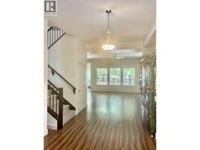 Coquitlam apartment for rent - A well-lit hallway with a staircase and a plant on the side.