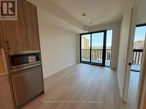 Toronto (Mount Pleasant West) condo for rent - A kitchen with a stainless steel refrigerator and microwave, wooden cabinets, and a view of a balcony with a railing.