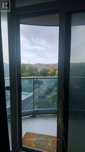 Markham (Unionville) condo for rent - A view from a window looking out at a parking lot and trees.