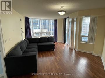 Markham (Unionville) condo for rent - A living room with a black couch and wooden floors.