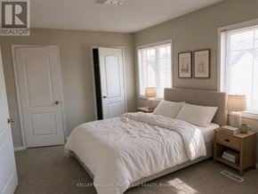 Toronto (Rouge) townhouse for rent - A bedroom with a large bed and a nightstand with a lamp.