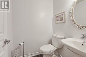 Toronto (Long Branch) townhouse for rent - A white bathroom with a toilet, sink, and mirror.