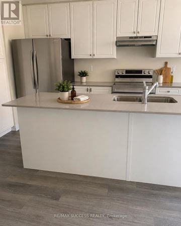 Hamilton (Stoney Creek Mountain) townhouse for rent - A kitchen with white cabinets and a stainless steel refrigerator.