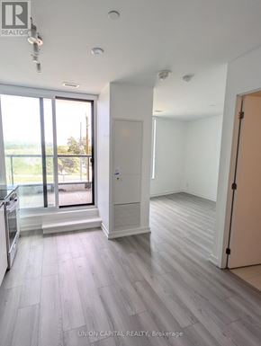 Toronto (Downsview-Roding-Cfb) condo for rent - A spacious room with wooden flooring and a large window overlooking a balcony.