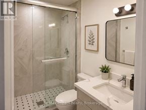 Oshawa (Taunton) apartment for rent - A bathroom with a white toilet, a sink, a mirror, and a shower with a glass door.