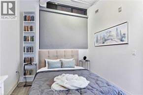 Guelph condo for rent - A bedroom with a bed, a bookshelf, and a painting on the wall.