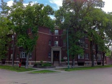 Winnipeg apartment for rent - A red brick building with trees in front.