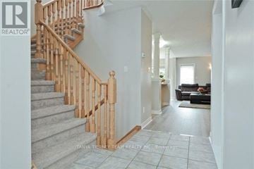 Whitby (Brooklin) townhouse for rent - A staircase with a wooden banister and a living room with a couch and a coffee table.