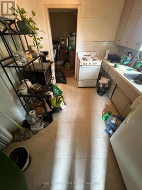 London East (East F) fourplex for rent - A kitchen with a white stove and a black shelf with various items on it.