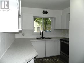 St. Catharines (Carlton/Bunting) townhouse for rent - A kitchen with white cabinets and a window.