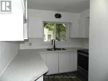 St. Catharines (Carlton/Bunting) townhouse for rent - A kitchen with white cabinets and a window.