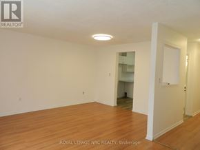 St. Catharines (Carlton/Bunting) townhouse for rent - A room with wooden floors and white walls, with a door on the right.