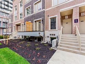 Vaughan (Vaughan Corporate Centre) townhouse for rent - A brick building with a small garden in front.