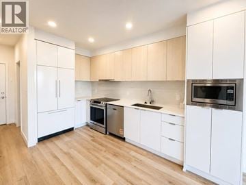 Tsawwassen apartment for rent - A kitchen with white cabinets and wooden floors.
