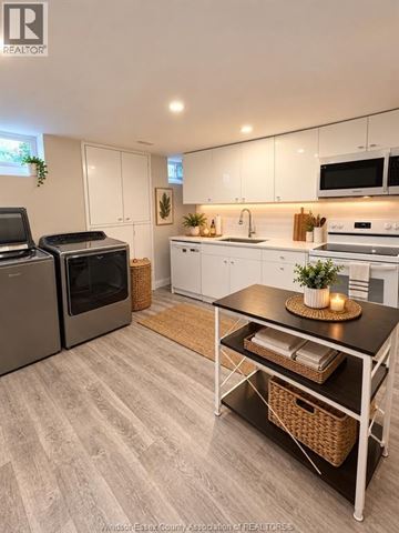 Tecumseh apartment for rent - A kitchen with white cabinets and a black table.