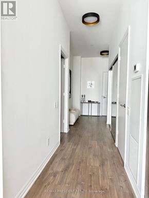 Toronto (Waterfront Communities) condo for rent - A hallway with white walls and wood flooring.