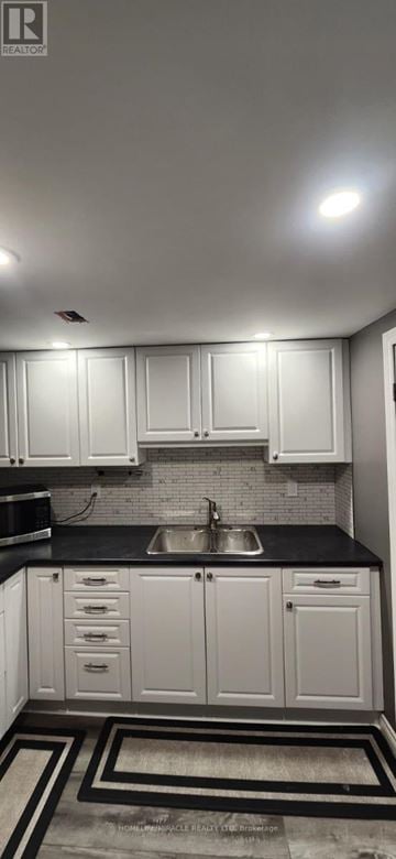 Oshawa (Centennial) apartment for rent - A kitchen with white cabinets and black countertops.