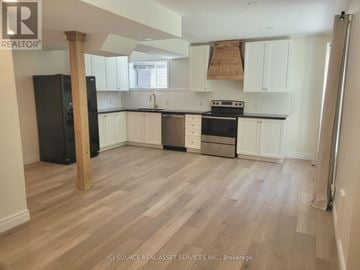 Wasaga Beach apartment for rent - A kitchen with white cabinets and a black fridge.
