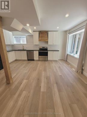 Wasaga Beach apartment for rent - A kitchen with wooden floors and white cabinets.
