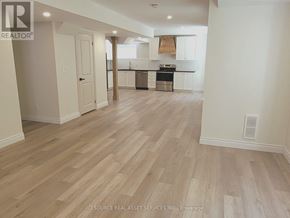 Wasaga Beach apartment for rent - A spacious kitchen with white cabinets and a wooden floor.
