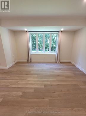 Wasaga Beach apartment for rent - A room with wooden flooring and a window with curtains.