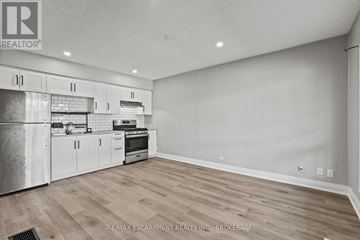 Welland (Prince Charles) multi-family for rent - A kitchen with white cabinets and a stainless steel refrigerator.