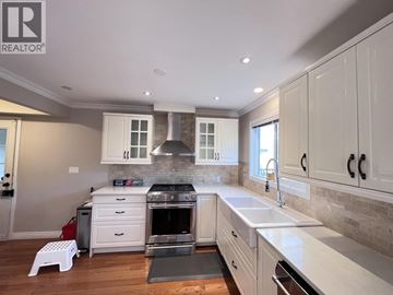 Coquitlam apartment for rent - A modern kitchen with white cabinets and a brick backsplash.