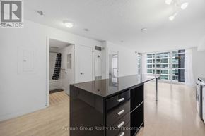 Toronto (Bayview Village) condo for rent - A large, empty room with a kitchenette and a view of a cityscape through the window.