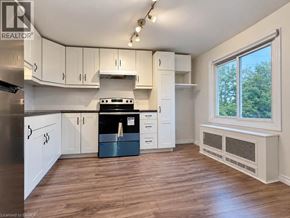 Brantford apartment for rent - A kitchen with white cabinets and a black stove top oven.