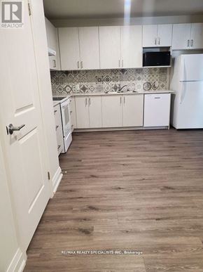 Hamilton (Beasley) condo for rent - A kitchen with white cabinets and a white fridge.