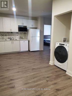 Hamilton (Beasley) condo for rent - A white fridge and washer in a kitchen with wooden floors.