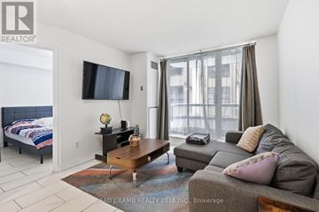 Toronto (Moss Park) condo for rent - A living room with a grey couch and a flat screen TV mounted on the wall.