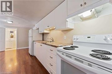 Hamilton apartment for rent - A white stove is in a kitchen with white cabinets and a white fridge.