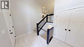 Grande Prairie apartment for rent - A white hallway with a black staircase and white cabinets.