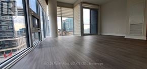 Toronto (Niagara) condo for rent - A spacious room with wooden flooring and large windows overlooking a cityscape.