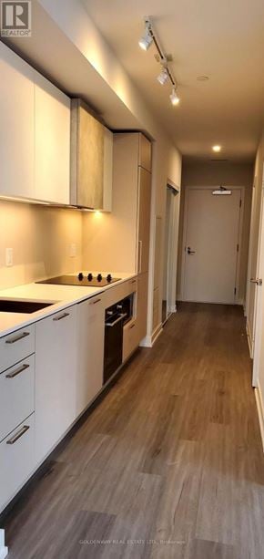 Toronto (Niagara) condo for rent - A kitchen with white cabinets and a wooden floor.