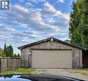 Hamilton apartment for rent - A wooden garage with a closed brown door is situated next to a pond.