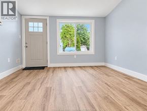 Amherstburg apartment for rent - A room with a wooden floor and a door leading to a balcony with trees visible outside.