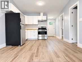 Amherstburg apartment for rent - A kitchen with a black fridge, white cabinets, and a wooden floor.