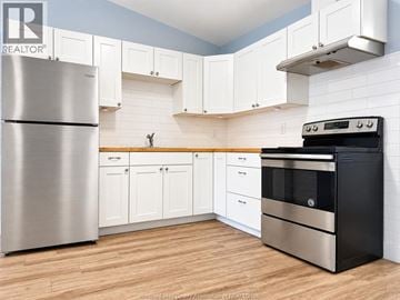 Amherstburg apartment for rent - A kitchen with a stainless steel refrigerator and a black oven.