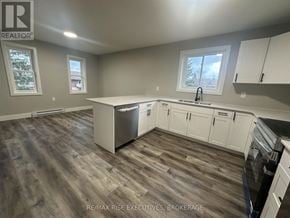 Gananoque triplex for rent - A kitchen with white cabinets and a wooden floor.