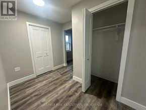 Gananoque triplex for rent - A room with a white door and a wooden floor.