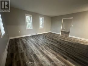 Gananoque triplex for rent - A room with wooden flooring and two windows.