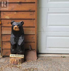 Severn (Washago) apartment for rent - A wooden bear statue sits on a stump with a sign that says "Welcome".