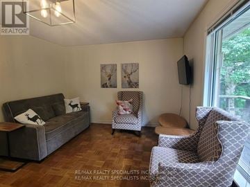Severn (Washago) apartment for rent - A living room with a grey couch, a chair with a patterned design, and a television mounted on the wall.